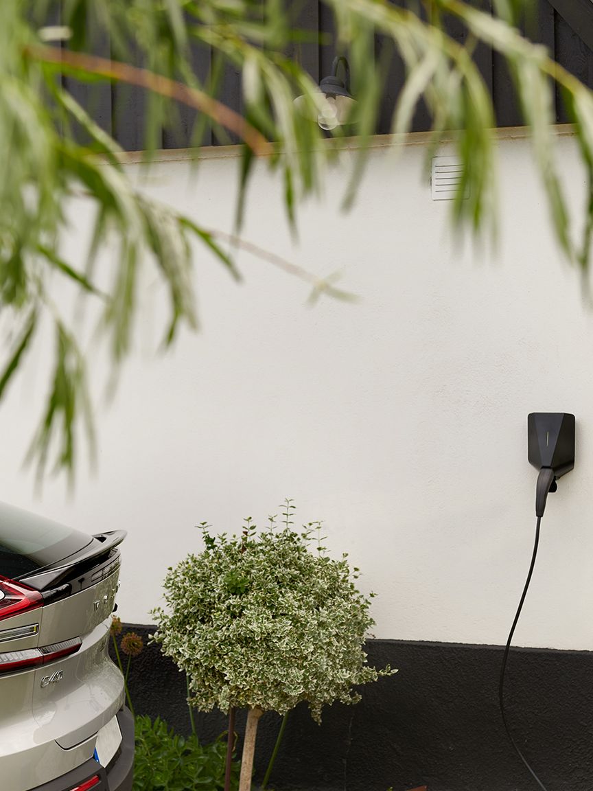 An electric car is loading in front of a modern house