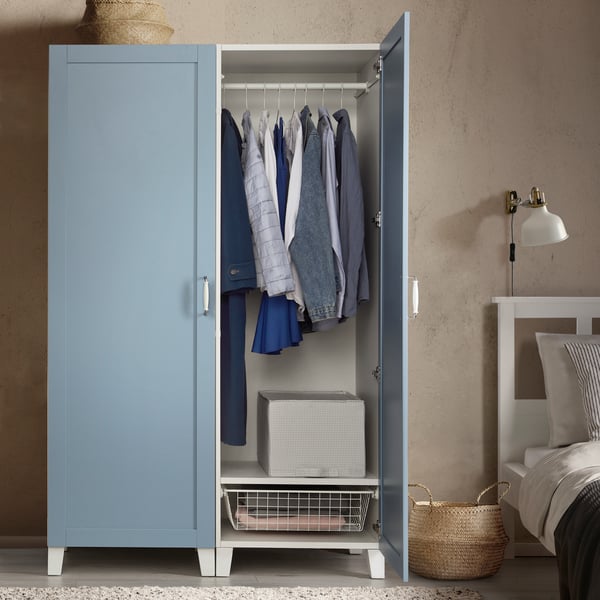 Un armadio PLATSA a due ante a battenti con piedini bianchi e ante azzurre