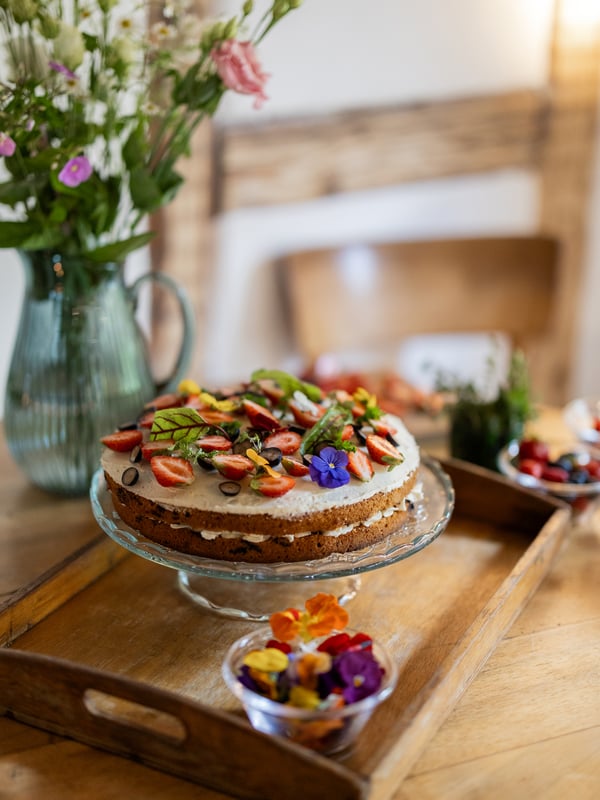 Close-up of a midsummer cake, decorated with flowers, lying on a cake platter standing on a tray.