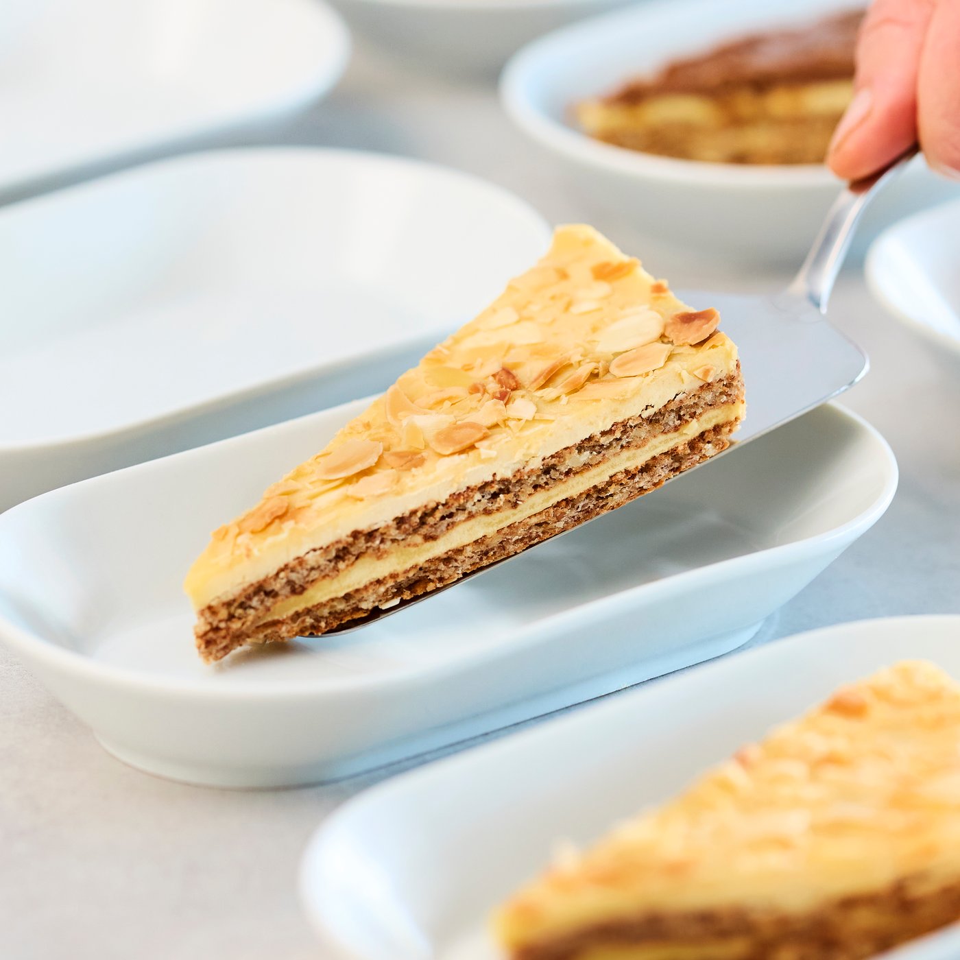 Porció de pastís d'ametlla sobre un plat de postres en color blanc