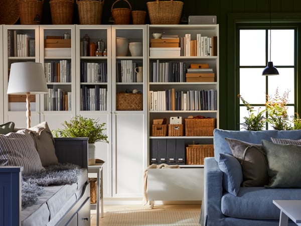 Ein Wand aus BILLY Bücherregalen. Offen und mit Türen. In einem Wohnzimmer. 