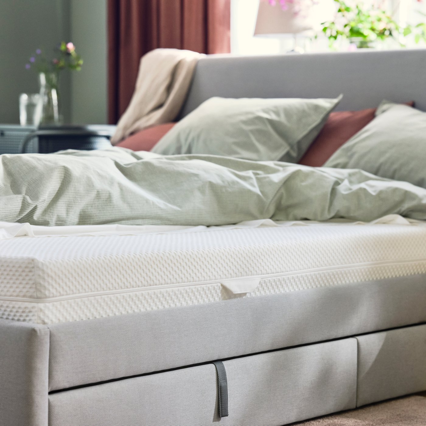 Un matelas en mousse ÅBYGDA ferme/blanc dans la chambre avec un sommier gris