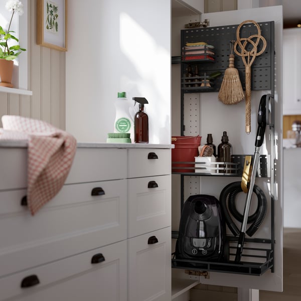 A sleek, gray storage cabinet features cleaning supplies, tools, and a vacuum cleaner inside, organized for easy access.