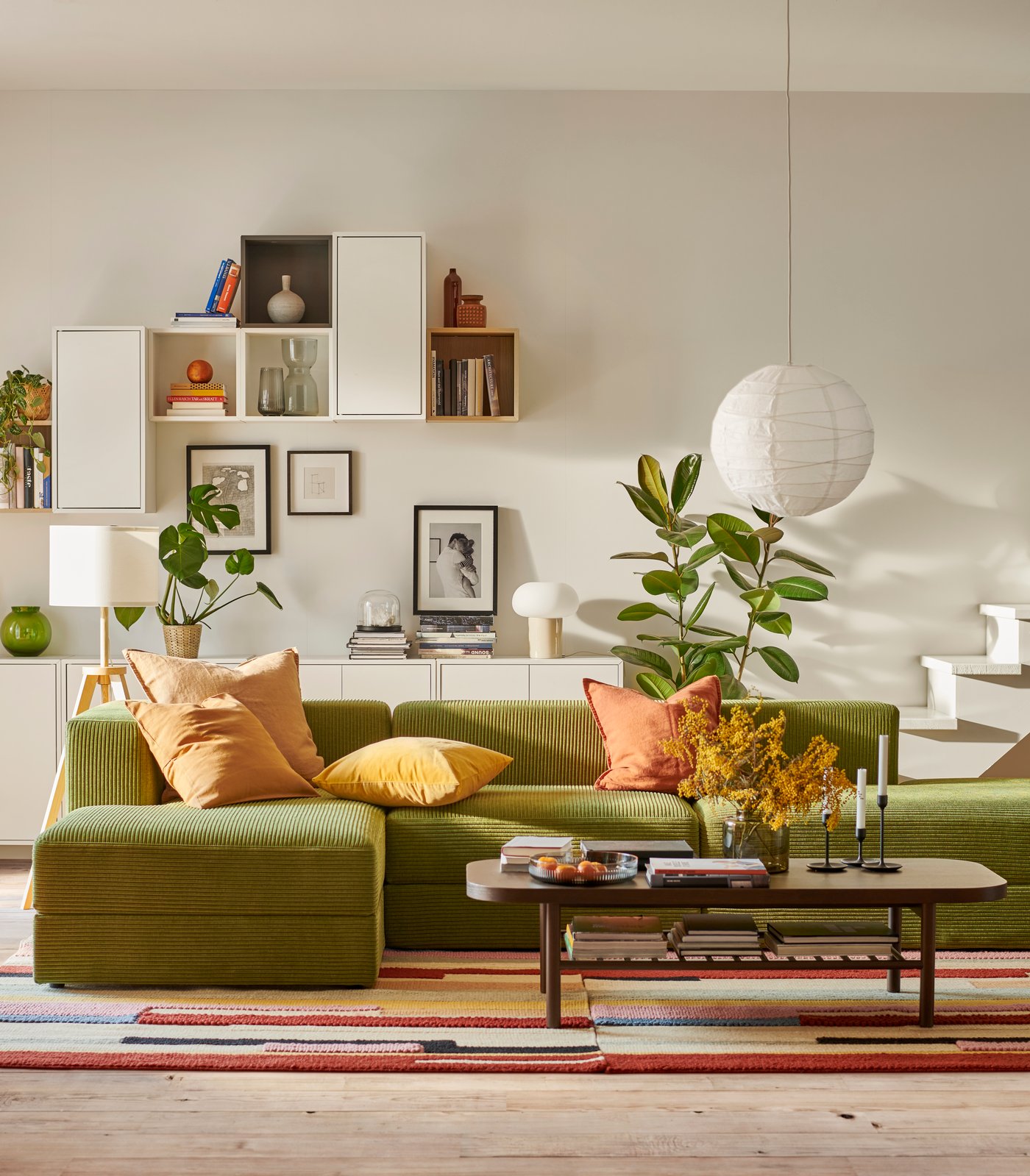 Ein JÄTTEBO Sofa mit Chaiselongue und ein LISTERBY Couchtisch stehen auf einem bunten BRÖNDEN Teppich im Wohnzimmer.