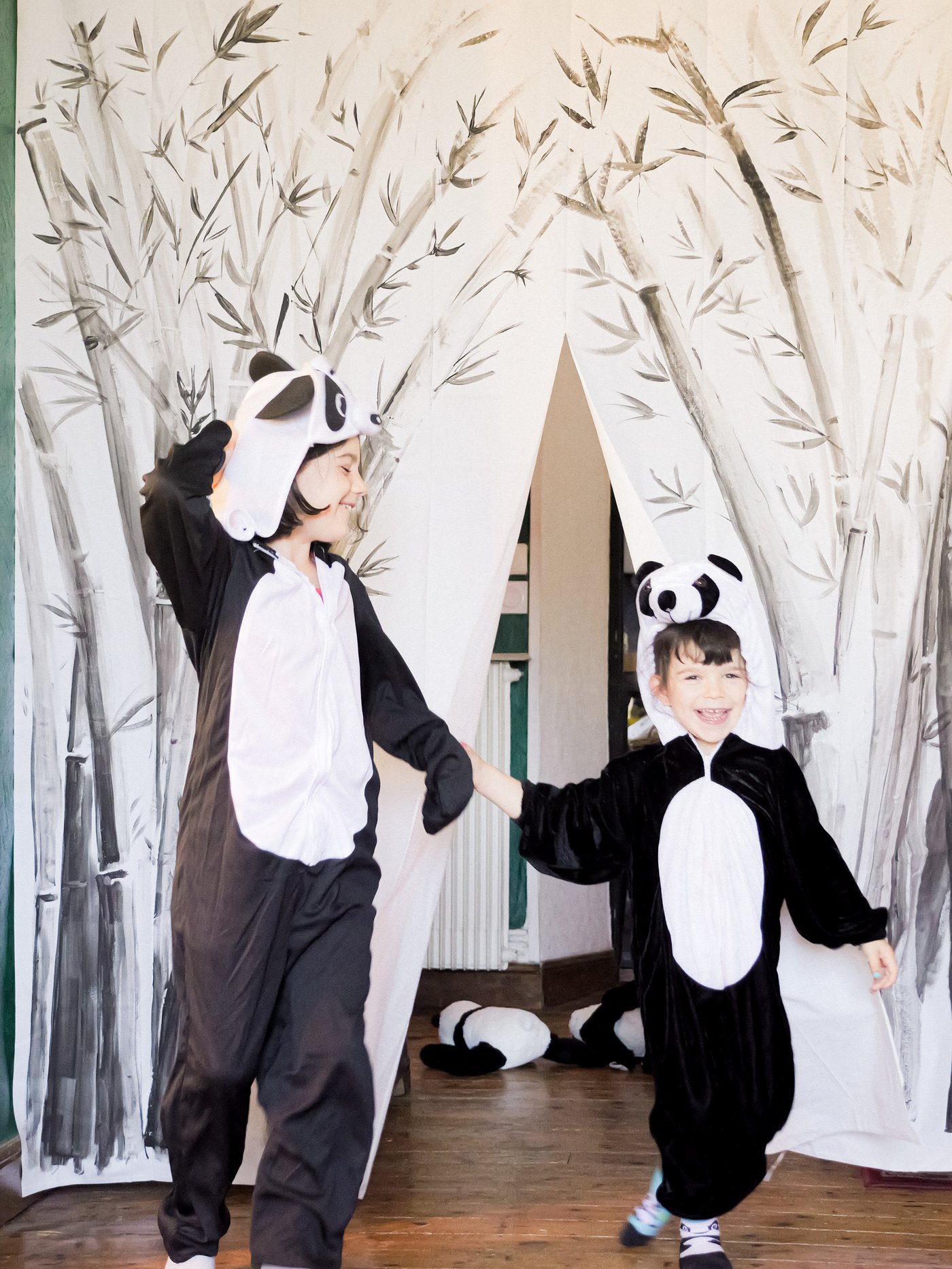 Deux enfants avec des costumes de panda saluent leur public devant un rideau de scène fabriqué à partir d’un rideau de douche BJÄRSEN décoré.