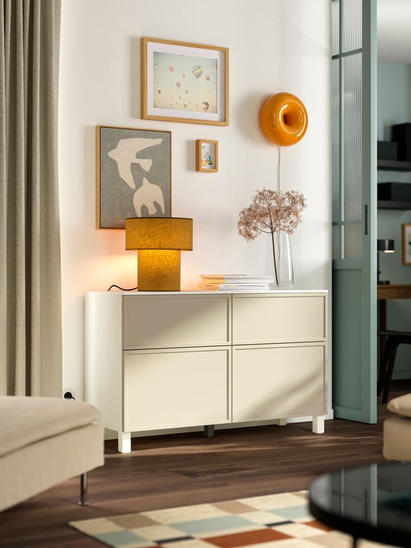 BESTÅ and KRUKMAKARE storage solution on wooden white legs in the living room.