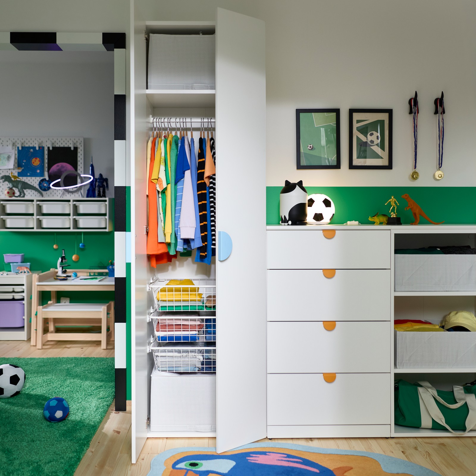 A children’s bedroom with walls painted green and white and a LASTARE storage system with clothes and soft toys.