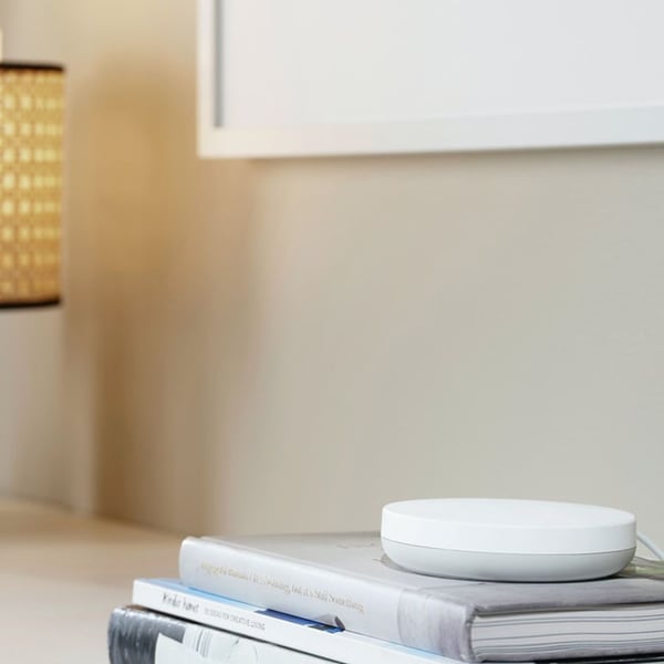 DIRIGERA hub for smart products from IKEA lying on a side table.