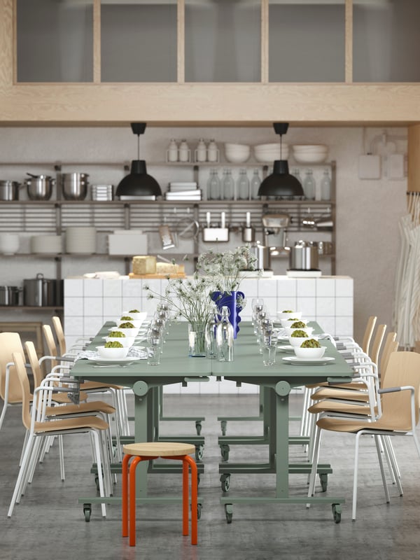 Several green MITTZON tables arranged for dining, paired with LÄKTARE conference chairs and an orange/pine DOMSTEN stool.