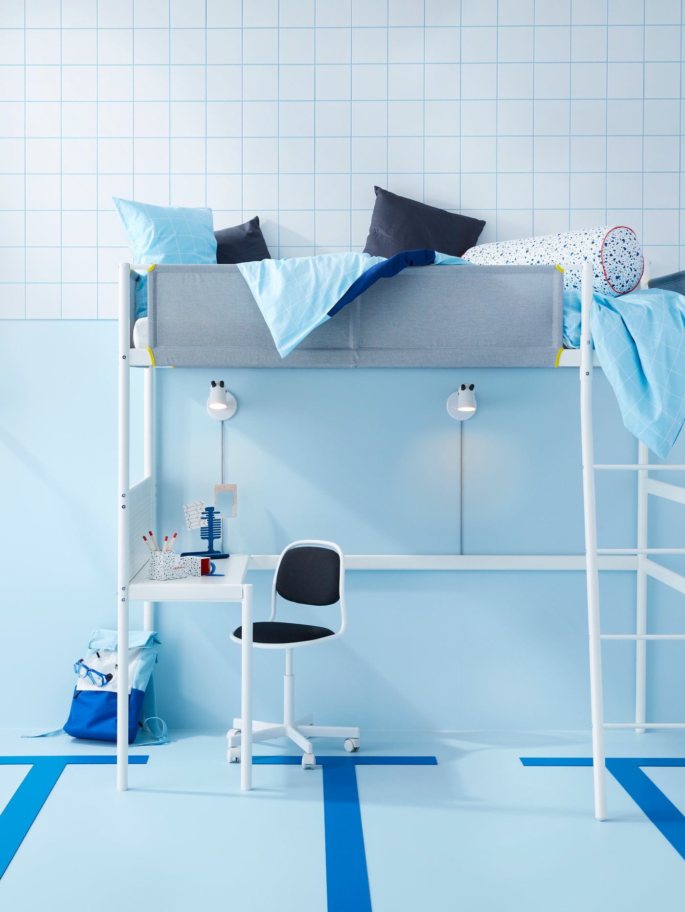 Dormitorio con pared azul claro, estructura de cama alta con almohadas, escritorio, lámpara de pared LED y silla de escritorio para niños.