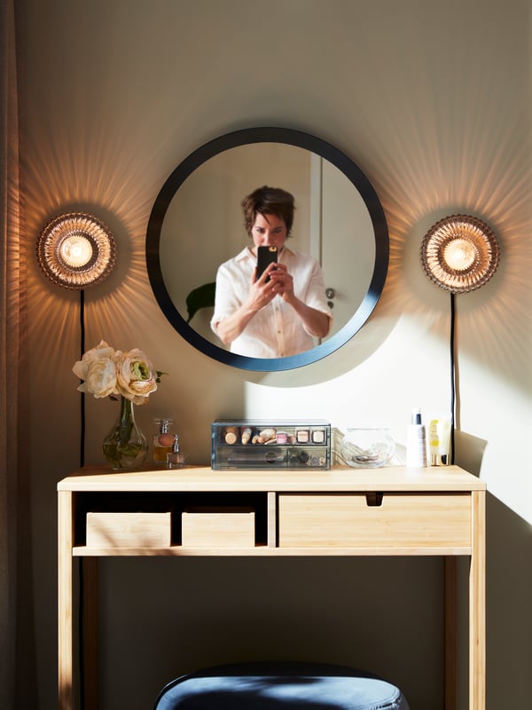 Eine Person fotografiert sich selbst im Spiegel einer Schminkecke.