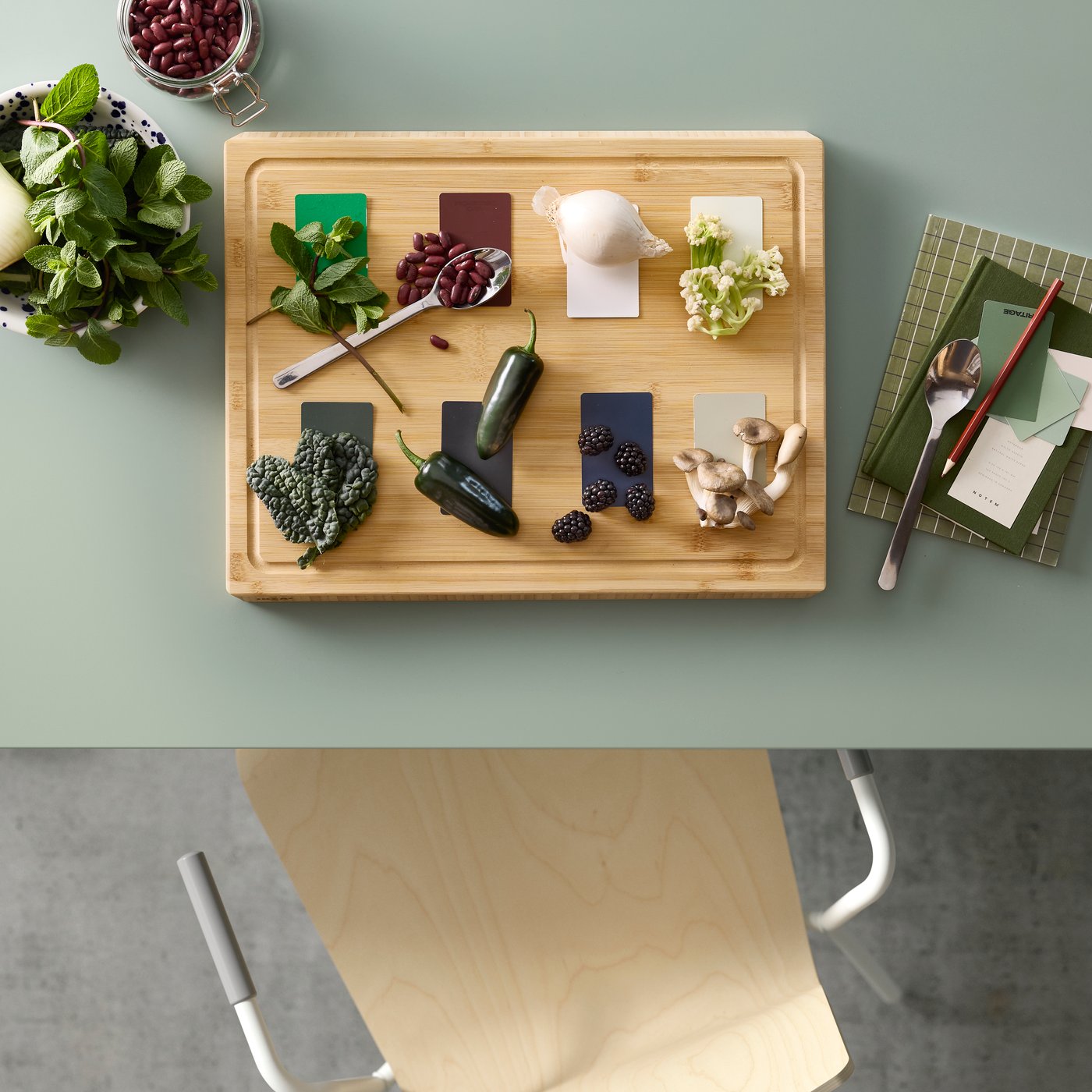 Blick von oben auf einen grünen MITTZON Klapptisch, der zum Essen gedeckt ist. Daneben steht ein LÄKTARE Stuhl aus Birkenfurnier mit weissem Gestell.