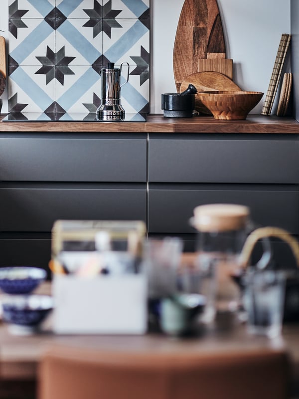 A modern kitchen with VOXTORP fronts in dark grey, with a wooden worktop and a kitchen tile backsplash.