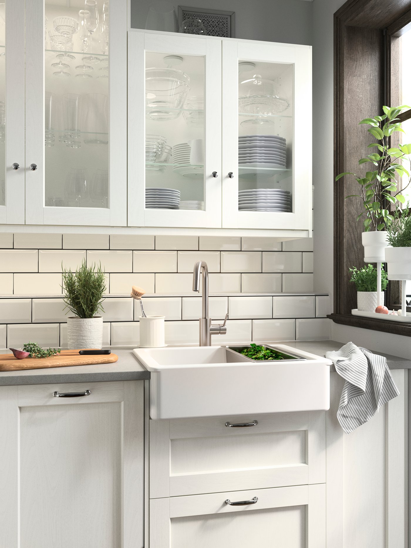 ห้องครัวพร้อมหน้าลิ้นชัก ENKÖPING/เอียนเชอปิง สีขาว อ่างซิงก์ HAVSEN/ฮาฟเซน สีขาว ที่เก็บของแขวนผนัง และกระถางต้นไม้สีขาวที่ปลูกสมุนไพรสีเขียว