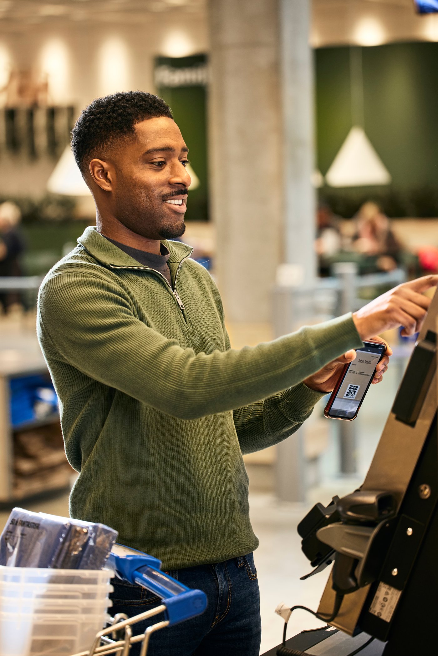 En person i grön tröja håller på att betala i kassan på ett IKEA varuhus.