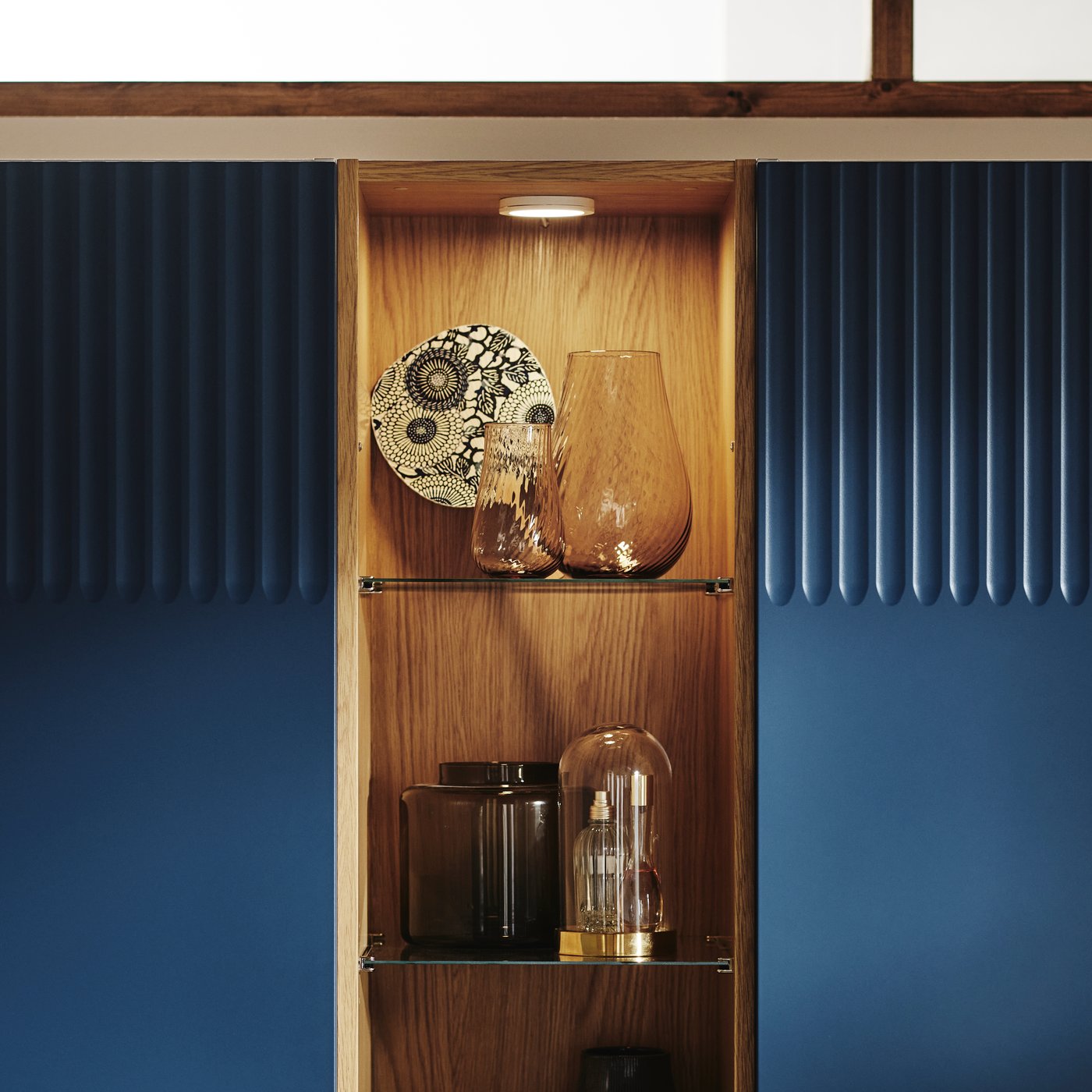 Close-up of PAX mid unit with integrated lighting and different vases and collectibles displayed on the glass shelves.