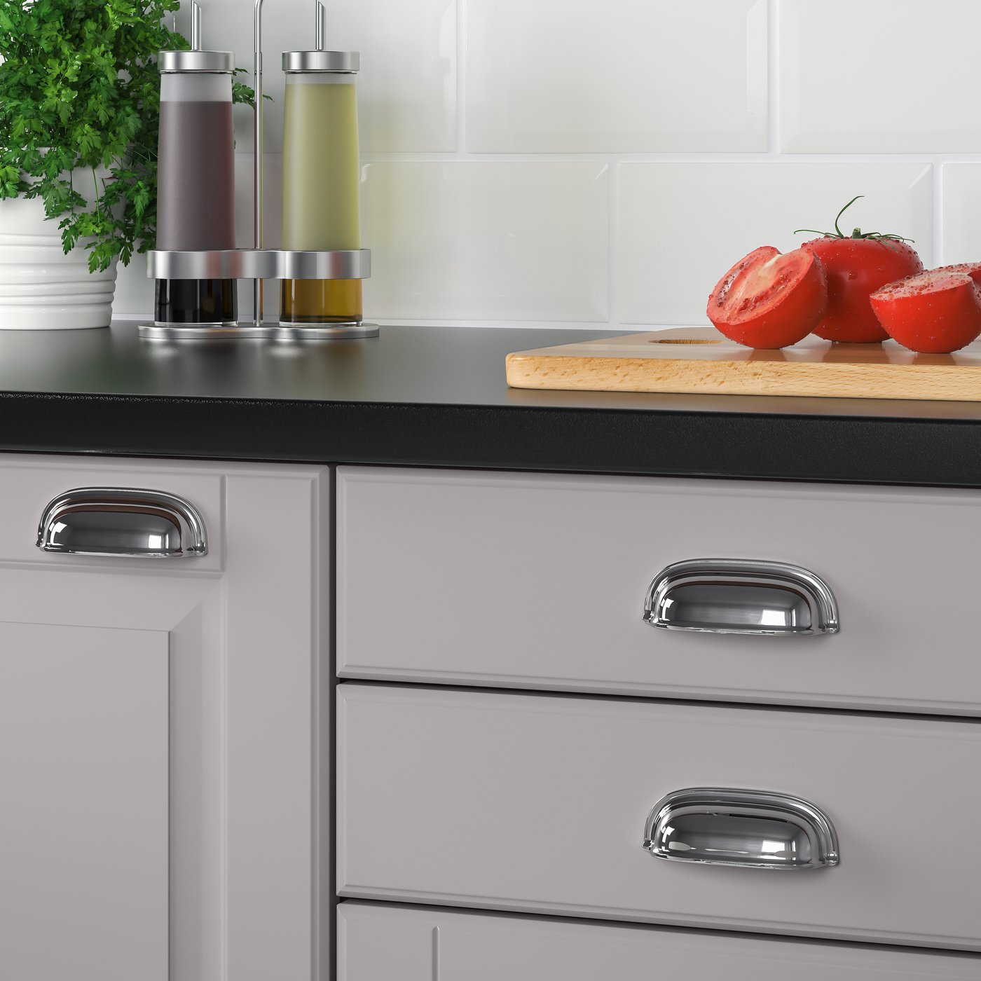 A grey kitchen fitted with ENERYDA chrome plated cup handles. On the countertop are oil, vinegar and some sliced tomatoes.