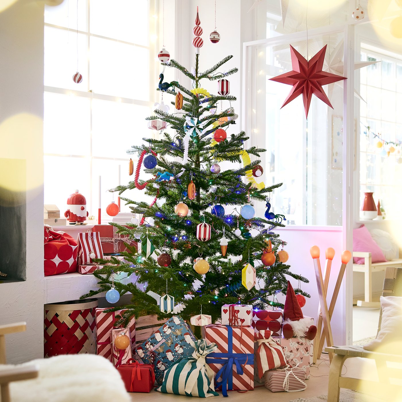 A VINTERFINT artificial Xmas tree with bright VINTERFINT tree decorations with lots of presents underneath.