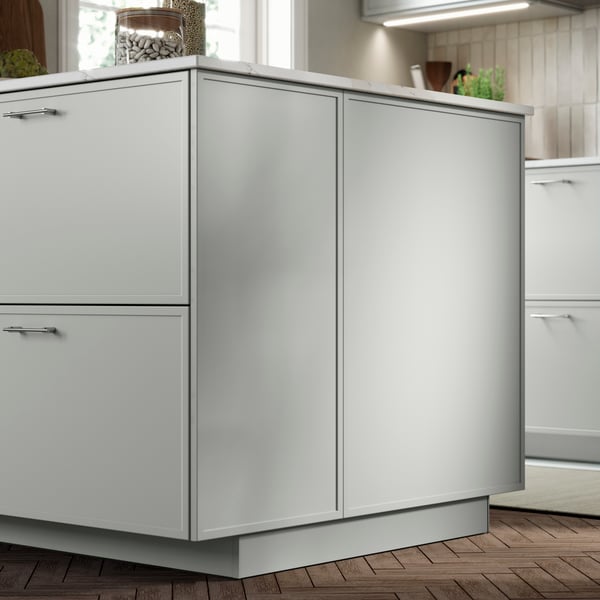 ASPUDDEN light grey fronts and cover panels on a kitchen island, in a modern kitchen with tiled walls.