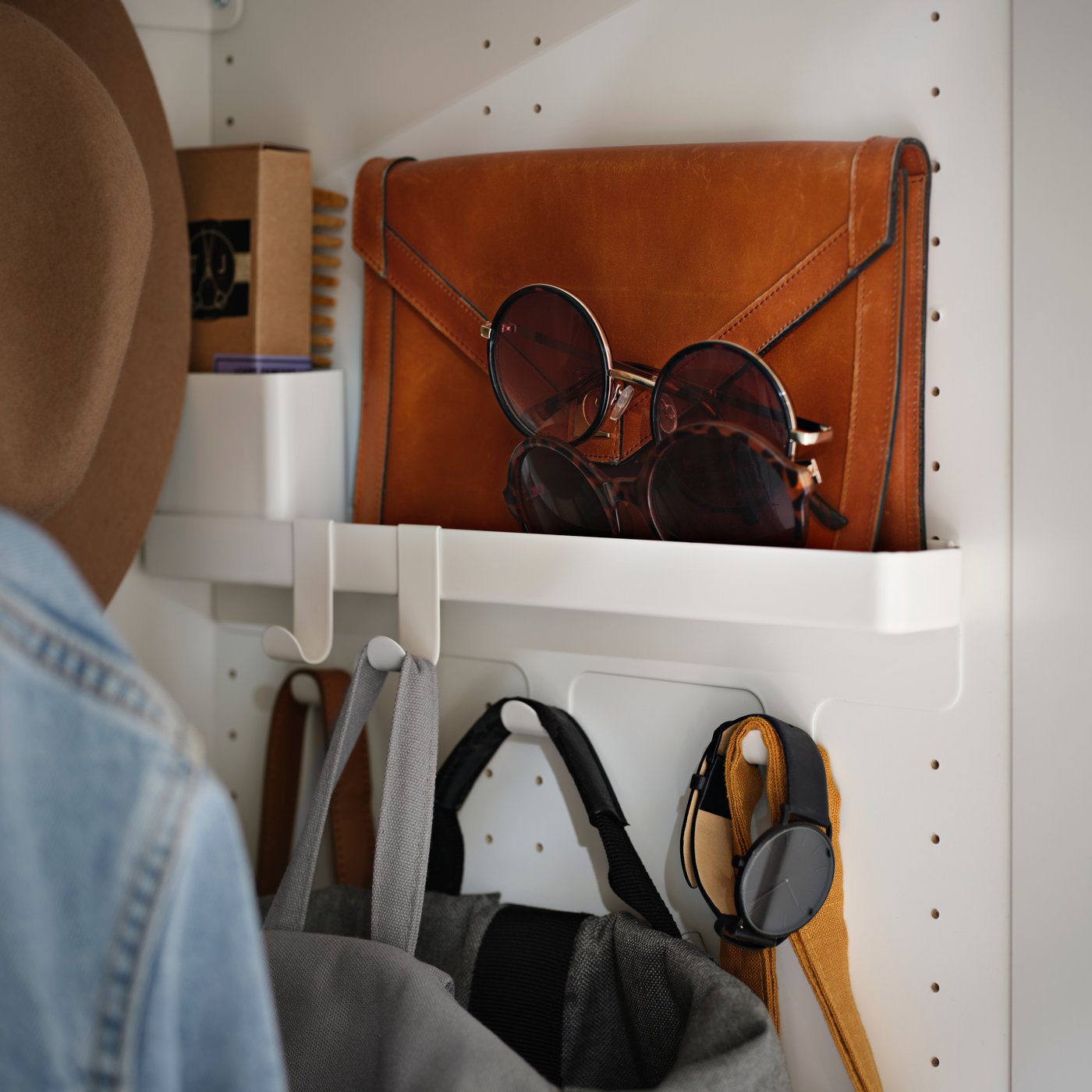 A wardrobe interior featuring the ALTARLIDEN hook rack with storage holding bags, accessories and small personal items.