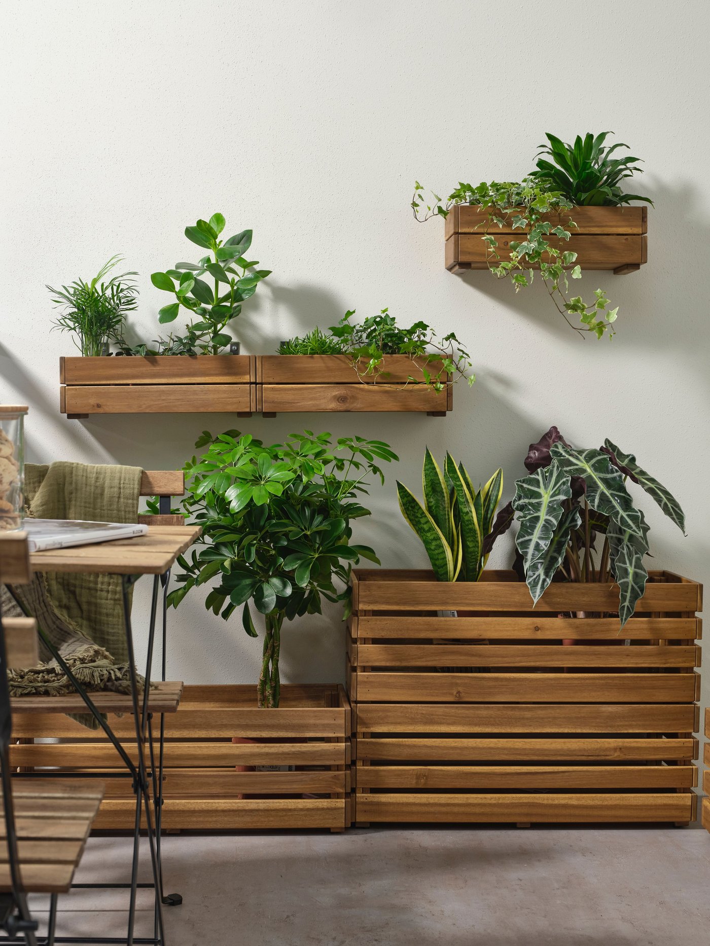 An outdoor space with several STJÄRNANIS planters. Some of them are hanging on the wall, filled with green plants.