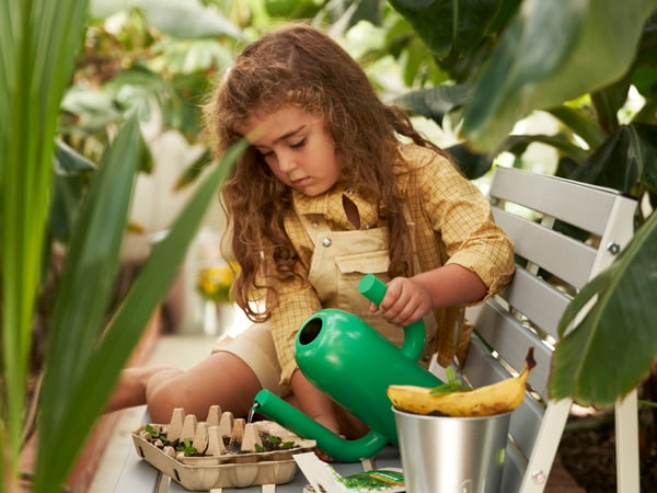 緑豊かな温室で、キッズがジョウロと苗を手に園芸を楽しむシーン。イケアのサステナブルな暮らしと子どものいる暮らしを伝えるビジュアル。