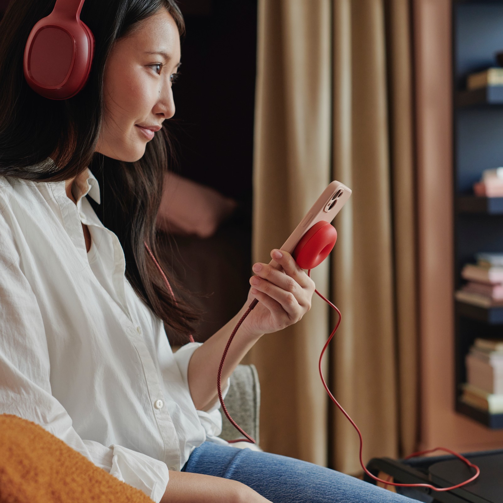 A person listens to music with headphones while charging a mobile phone with a VÄSTMÄRKE wireless charger.