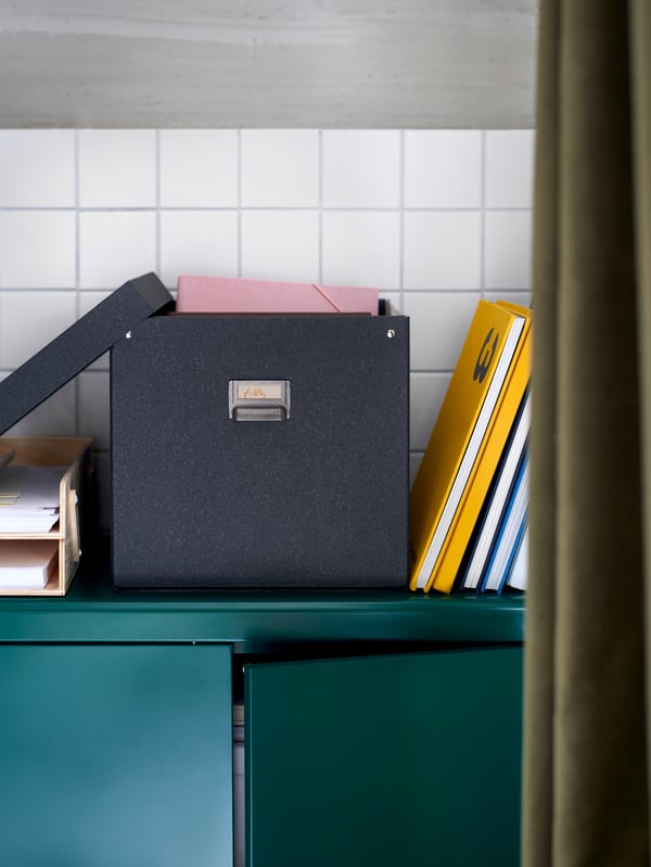 A blue paper storage box with the lid off and books leaned up against it