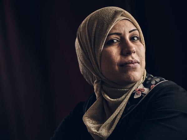 A portrait of Abeer Almnajed, a seamstress at the social business Jordan River Foundation, against a black background.