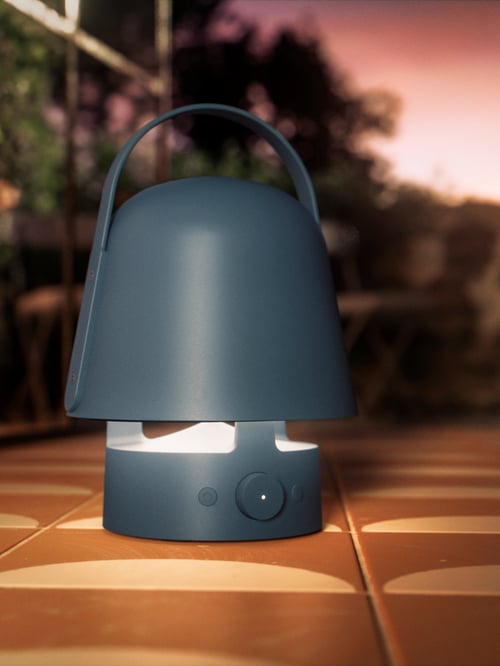 A VAPPEBY outdoor Bluetooth speaker lamp in blue, on a light-brown and cream-coloured tiled surface.