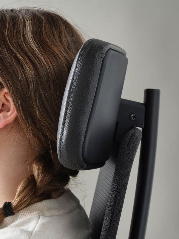 A close-up of a woman with her head resting against a leather style black JÄRVFJÄLLET office chair.