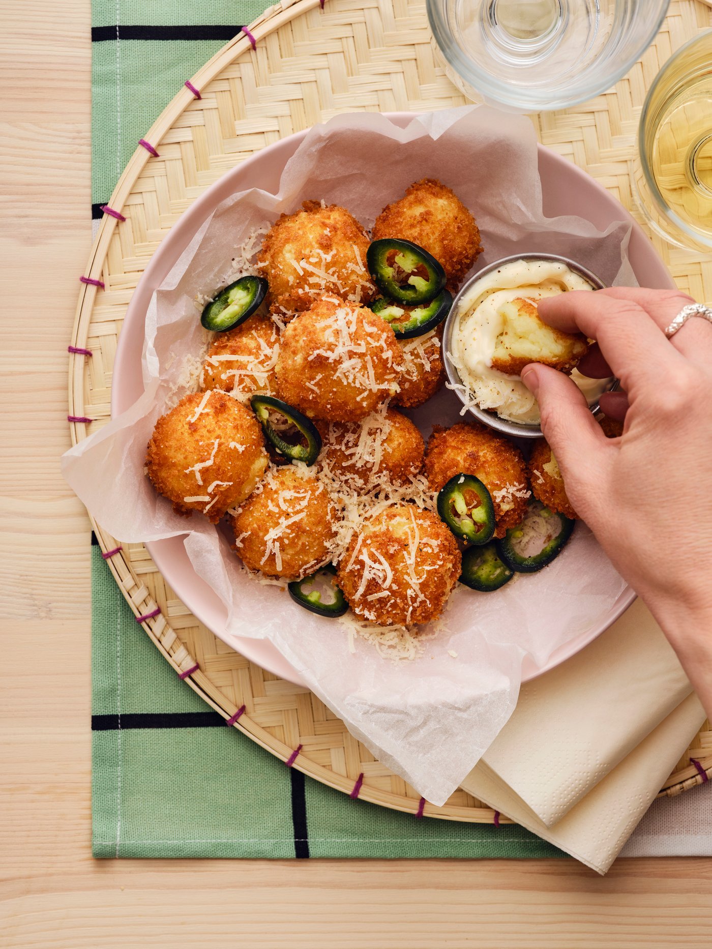 Main d’une personne plongeant une croquette préparée à partir de purée de pommes de terre ALLEMANSRÄTTEN dans une sauce crémeuse.
