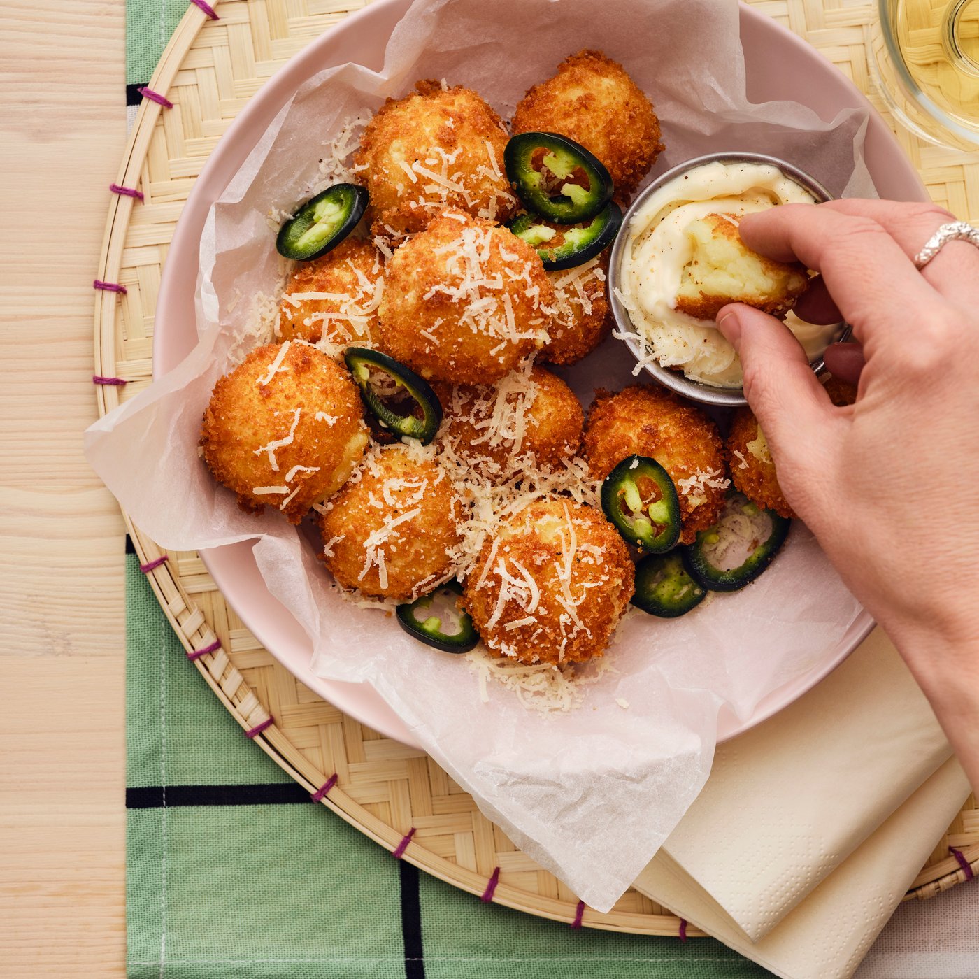 Mãos de pessoa mergulham um croquete de um prato com puré de batata ALLEMANSRÄTTEN num molho cremoso.
