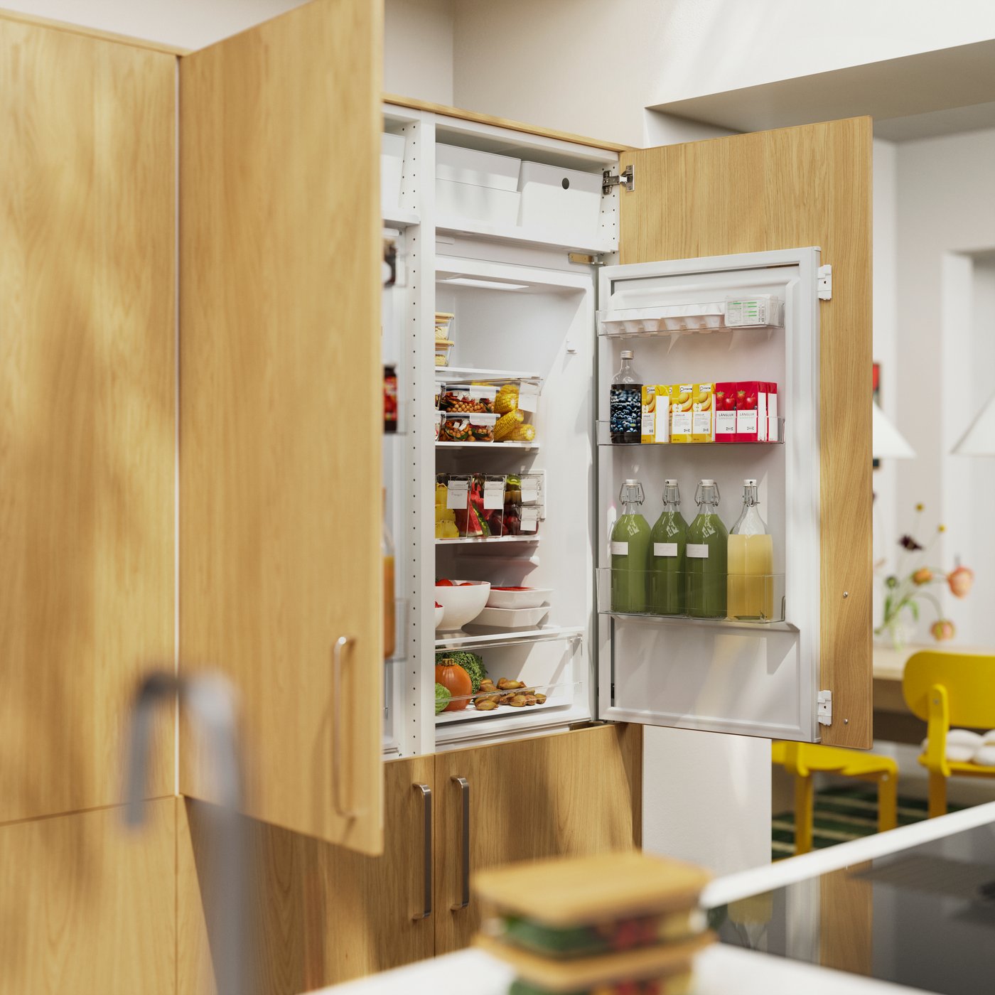 The doors of two SUPERKALL built-in refrigerators with SINARP fronts in oak veneer are open, showing food items inside.