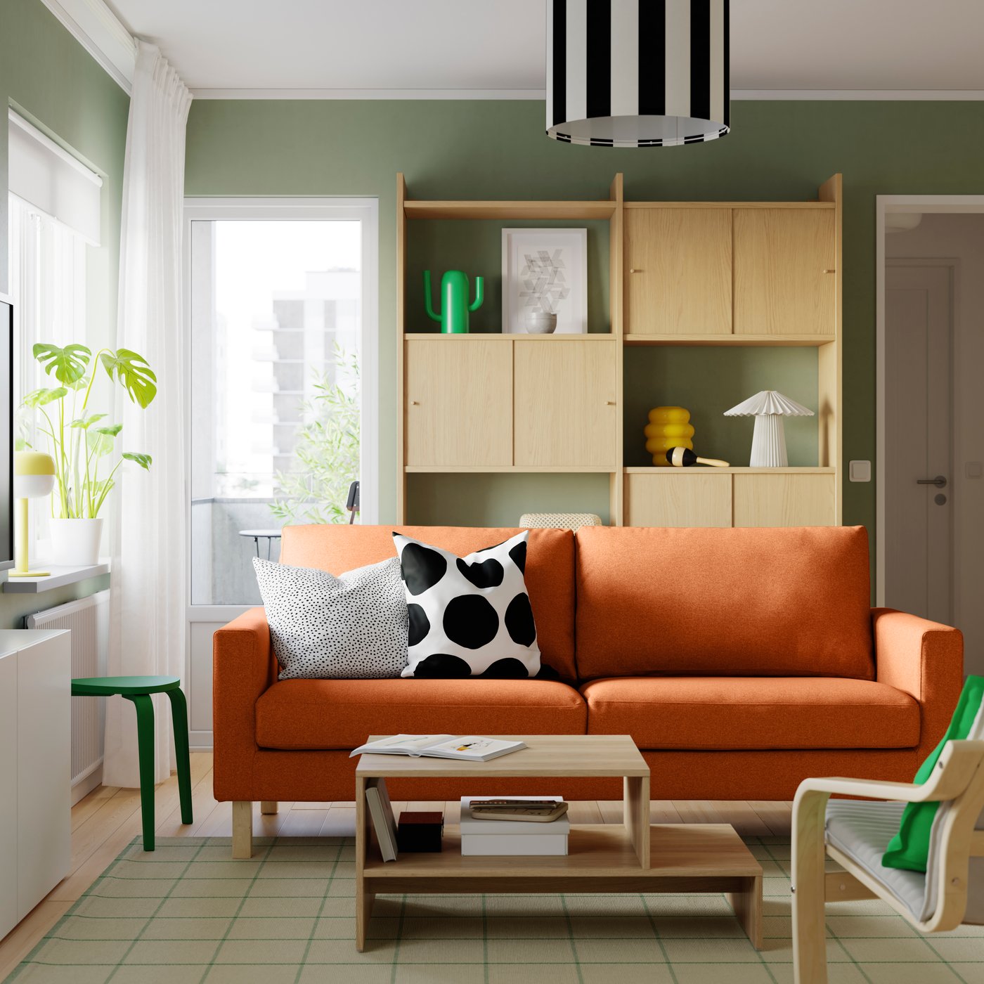 A red-brown SALTSJÖBADEN 3-seat sofa, with a couple of extra cushions lying on it, stands in a bright room.