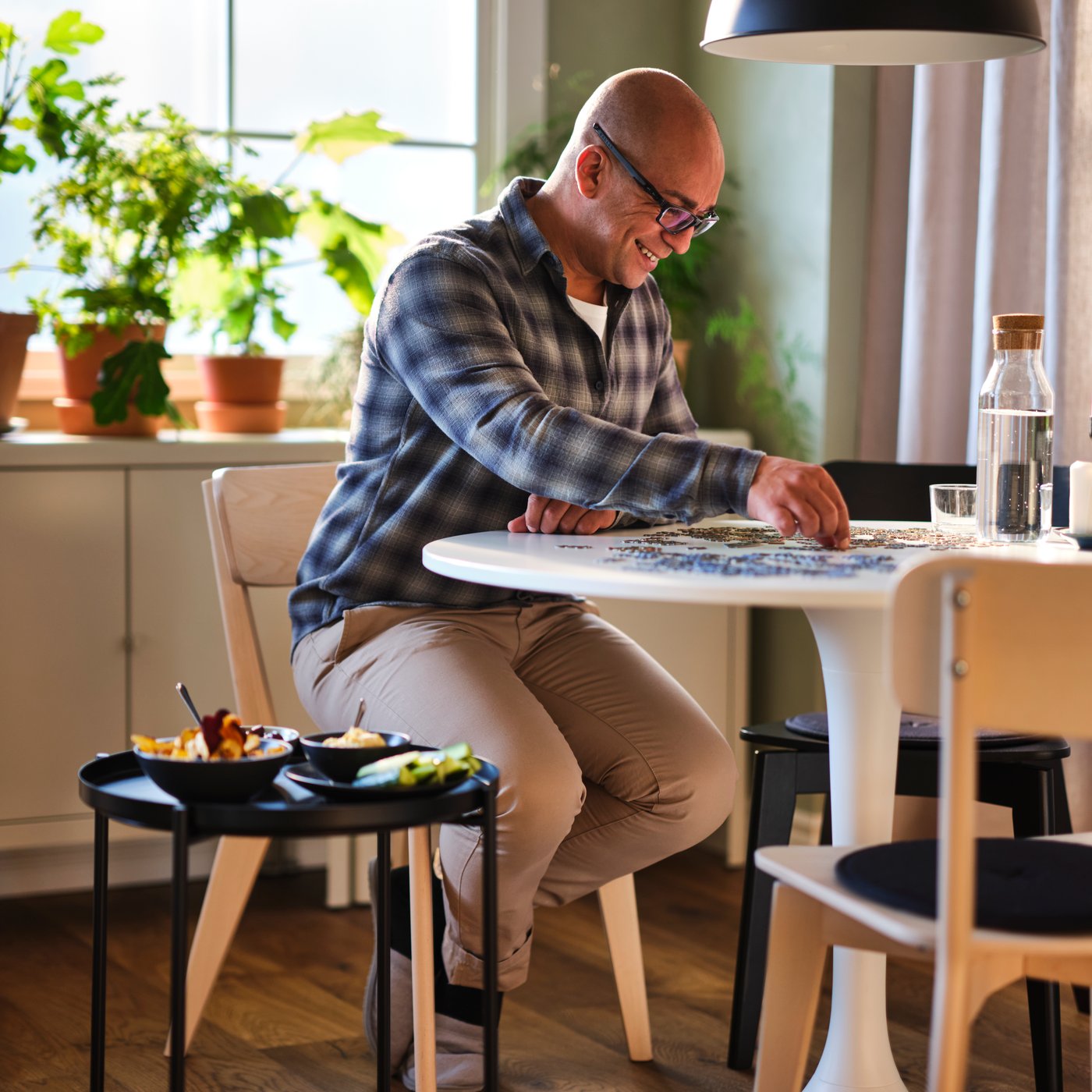 A white/white DOCKSTA table in the dining room with a man doing a puzzle on it.