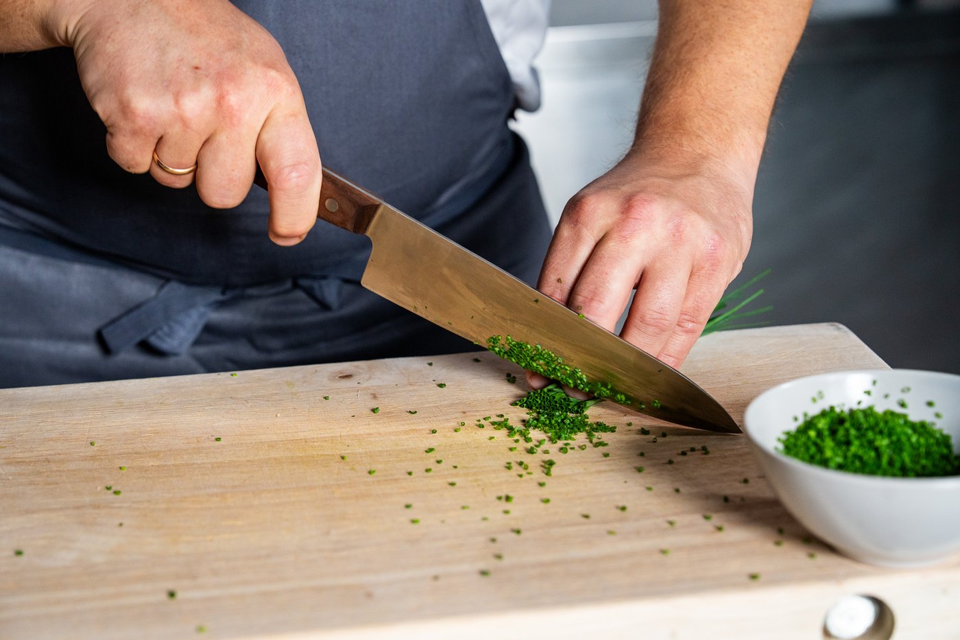 En kokk kutter gressløk med en kniv.
