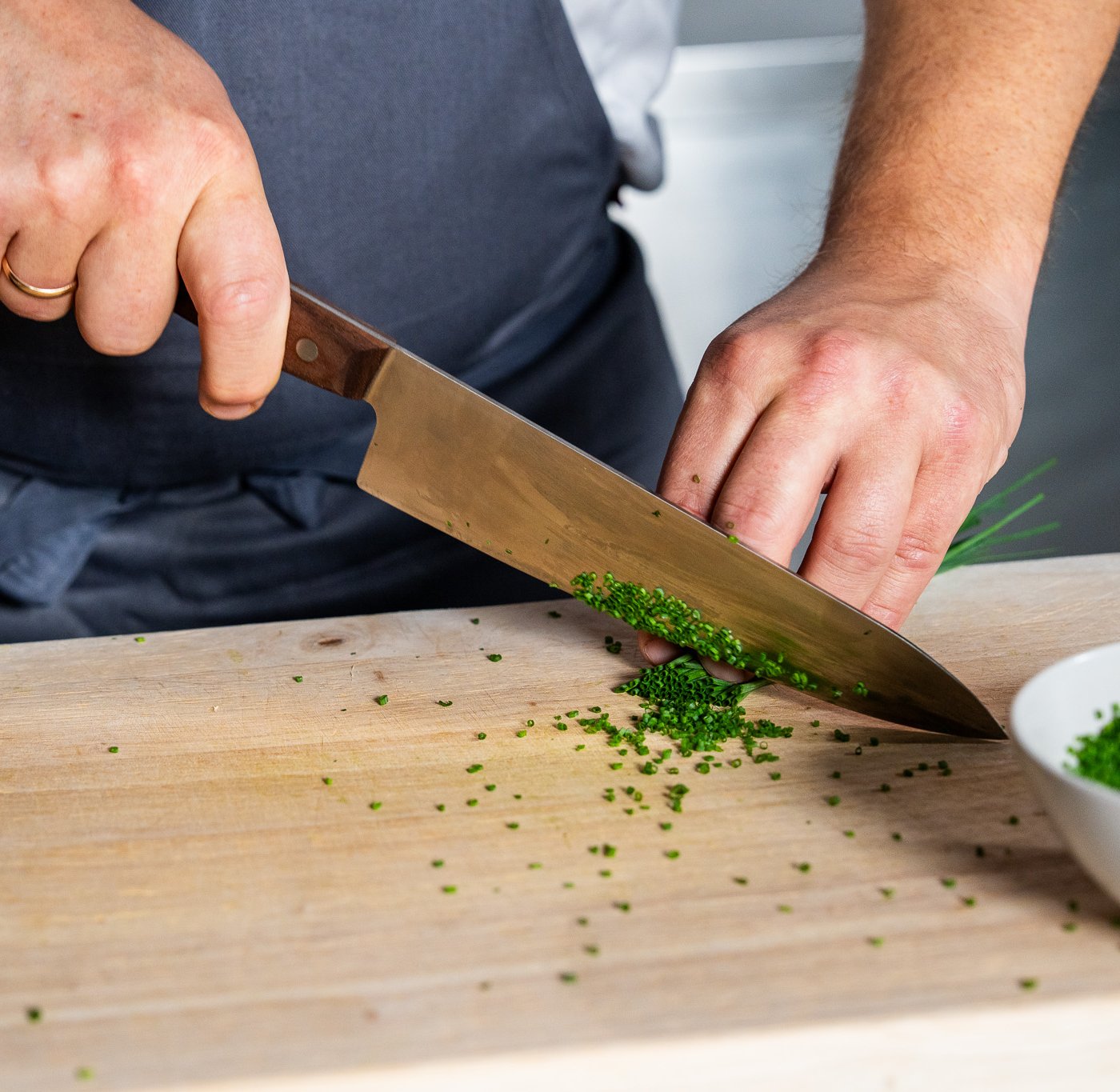 En kokk kutter gressløk med en kniv.