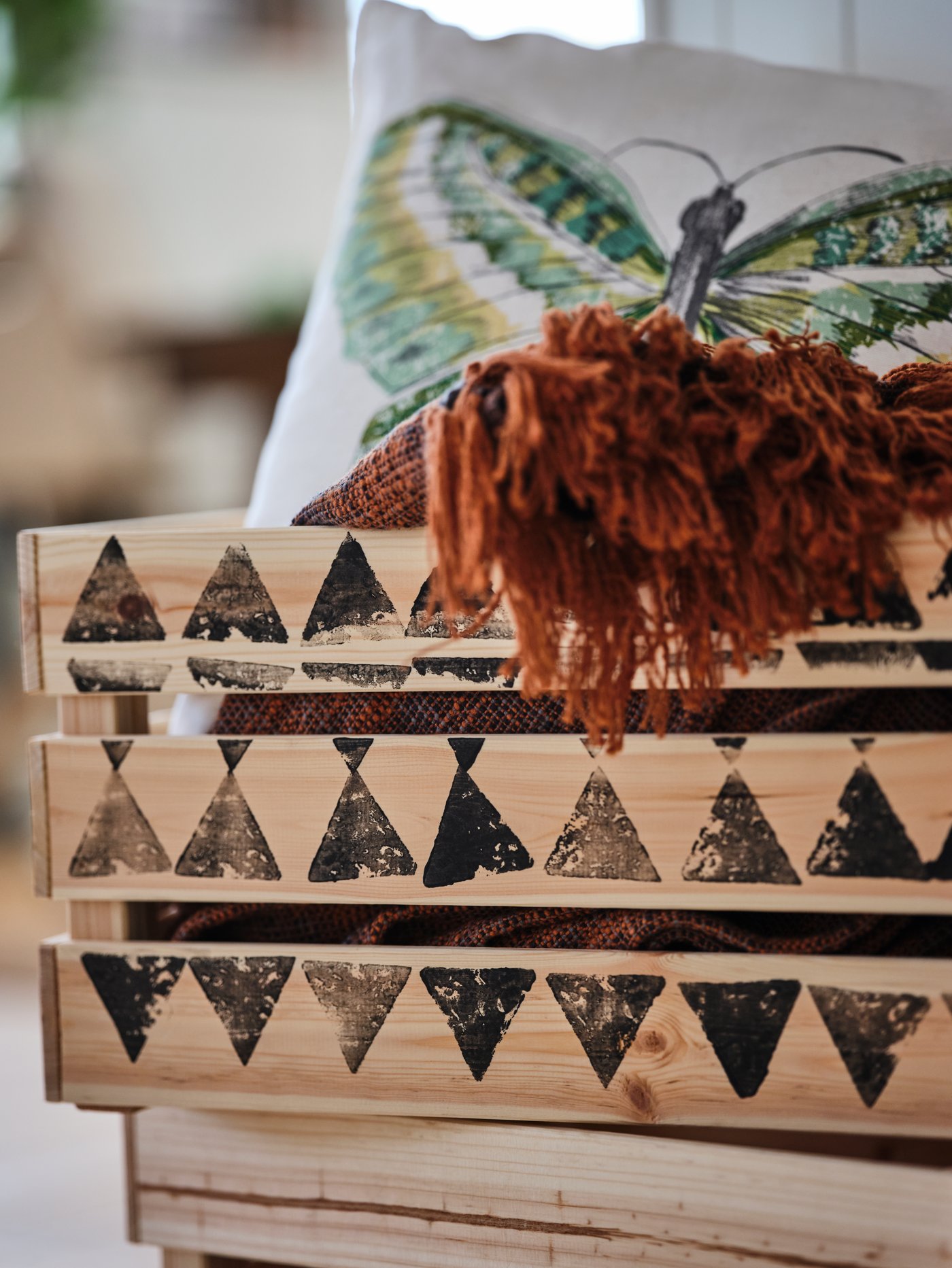 Odd textiles flowing over the top of a KNAGGLIG pine box which in turn is decorated with a potato-stamped pattern.