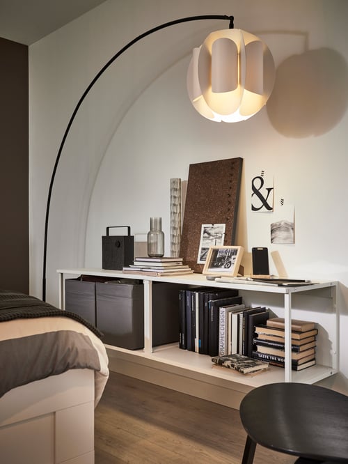 Living room with a white open shelving unit, an arched floor lamp base with a pendant lamp shade, and a brown memo board.