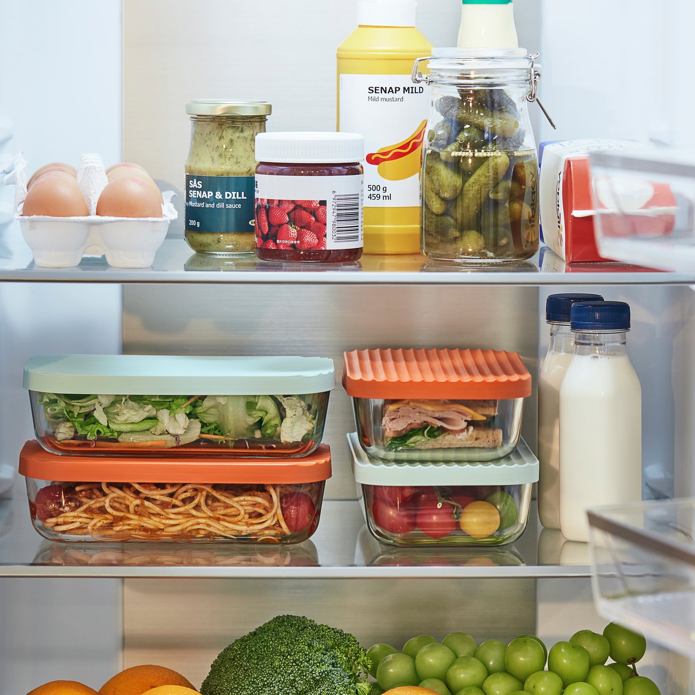 Open fridge with clear glass storage containers filled with food.