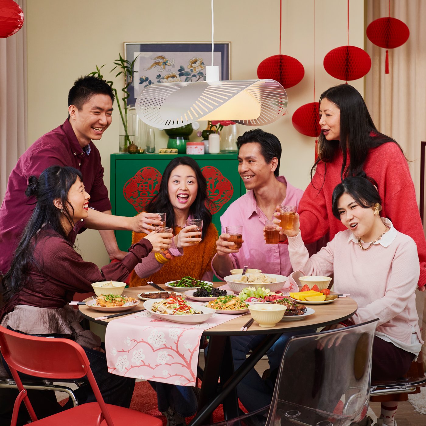 Six persons are celebrating Lunar New Year in a dining area with festive food and FÖSSTA decorations and tableware.