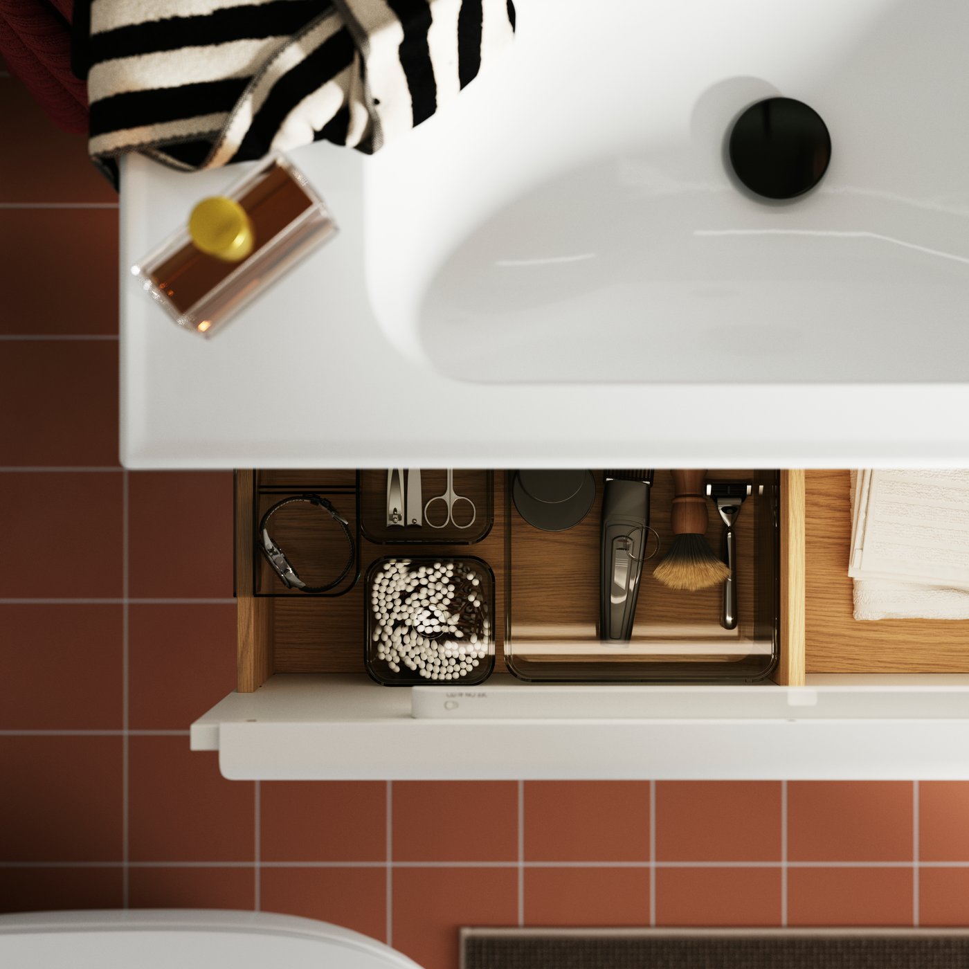 An open bathroom drawer displaying organised grooming tools and beauty items, with terracotta tiles visible below.