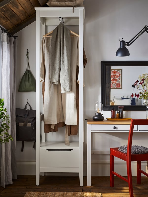 Objects made of light, untreated wood placed along a wall in a white room, one of them a slimline HEMNES desk with drawers.
