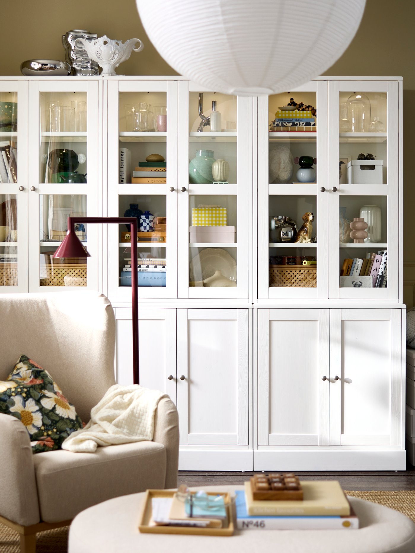 A living room featuring a white HAVSTA storage combination with glass doors, displaying decorative items and books.