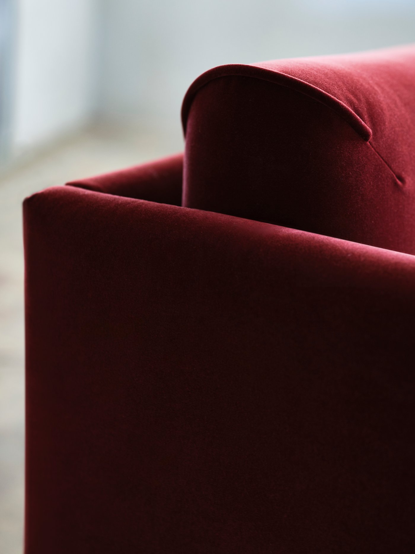 A close-up of the soft armrest on a red-brown ÄPPLARYD sofa.