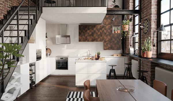 A METOD kitchen in white, with stairs to the side and a landing above, a kitchen table with three chairs and three stools.