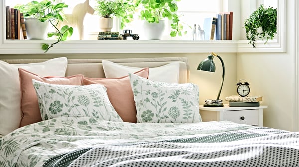 A light pink LAGERPOPPEL cushion cover in the bedroom