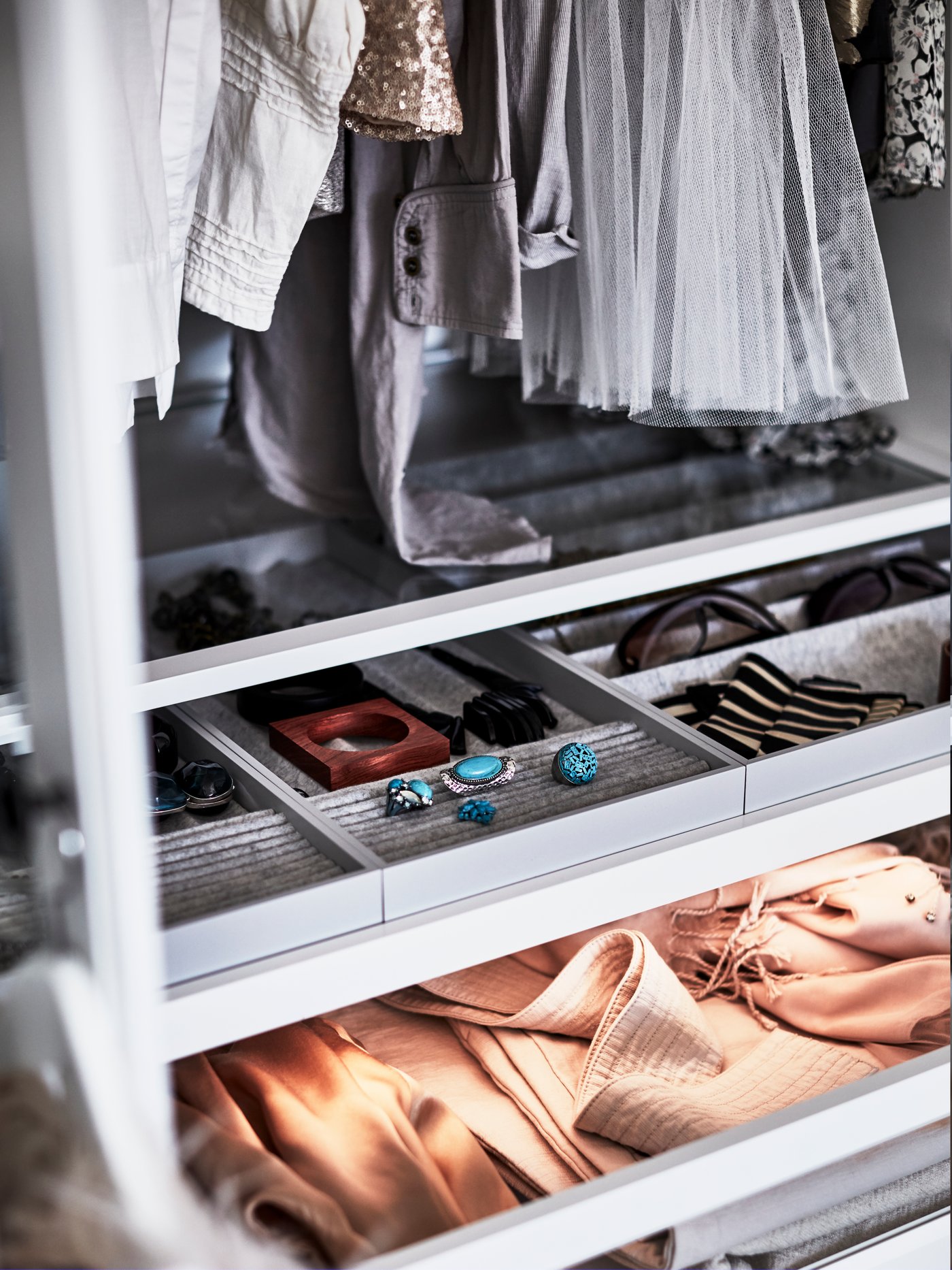 White PAX wardrobe showing the inside of the wardrobe with KOMPLEMENT interior fixtures and pull out trays with accessories organisers. 