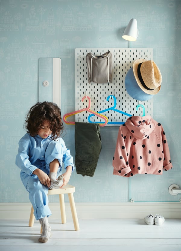 SKÅDIS appenditutto da parete bianco con alcuni vestiti e accessori per bambini.